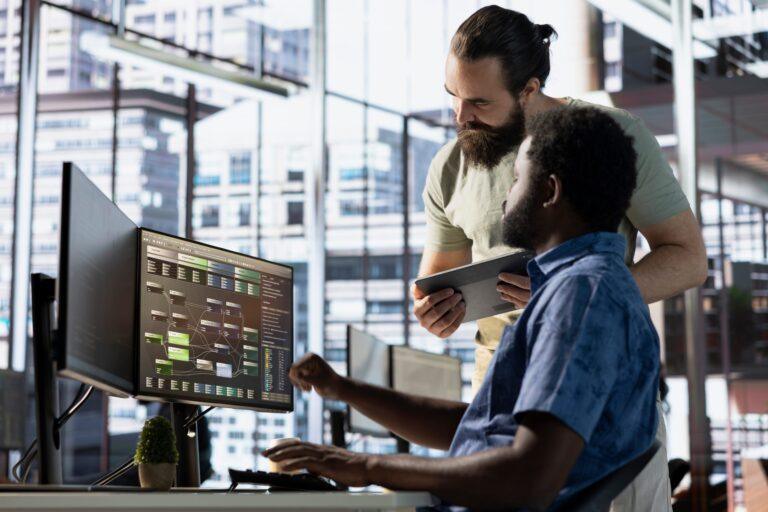 Deux collègues analysant des données sur un écran avec des outils technologiques avancés comme Power BI et Synapse Analytics.