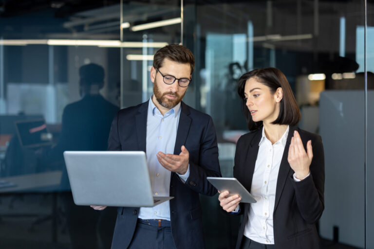 Un homme et une femme en discussion devant un ordinateur portable, travaillant sur une analyse stratégique personnalisée dans un bureau moderne.